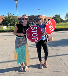 Two happy woman holding STOP signs in the parking lot